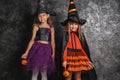 Cute little girls dressed as witches for Halloween near dark wall