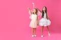 Cute little girls in fairy costumes with wings and magic wand on pink background. Space for text Royalty Free Stock Photo