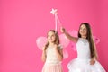 Cute little girls in fairy costumes with wings and magic wand on pink background. Space for text Royalty Free Stock Photo