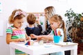 Cute little girls with interest fold geometric figures on desk in playroom. Educator with boy learn letters and numbers