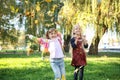 Cute little girls playing with leaves in autumn park