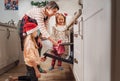 Cute little girls in red Santa hats with mother making homemade sweet biscuits. They putting baking sheet in hot oven. Christmas Royalty Free Stock Photo