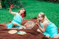 Cute little girls sitting on blanket on grass in backyard and show their dirty with painted hands, painting Easter eggs Royalty Free Stock Photo