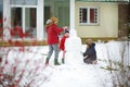 Cute little girls and their grandma building a snowman in the backyard. Cute children playing in a snow. Royalty Free Stock Photo