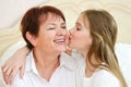 Cute little granddaughter child kissing smiling old grandmother on cheek Royalty Free Stock Photo