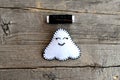 Cute little Halloween ghost ornament and black thread isolated on old wooden background. Hand toy is made of white felt. Step