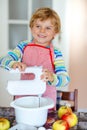 Cute little happy blond preschool kid boy baking apple cake and muffins in domestic kitchen. Funny lovely healthy child Royalty Free Stock Photo