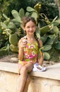 Cute cute little happy girl eating ice cream horn dirty on cactus background of plant. Royalty Free Stock Photo