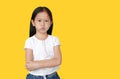 Cute little hispanic Asian child girl with arms crossed and angry about something on yellow background with copy space. Person