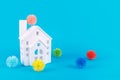 Cute little house and plastic balls as viruses on blue. Epidemic, social isolation, coronavirus COVID-19 concept