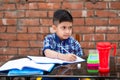 Cute little Indian/Asian school kid studying on study table , writing on notebook with pencil