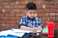 Cute little Indian/Asian school kid studying on study table , writing on notebook with pencil