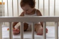 Cute little infant toddler baby girl kid sitting playing Rainbow Pop it finger fidget toy in white crib in white summer Royalty Free Stock Photo