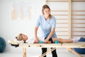 Little injure girl lying on massage table and exercising with young female doctor