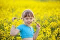 Cute little kid in blue t-shirts having fun in yellow field outdoor. Cheerful little girl with pigtails onnature background Royalty Free Stock Photo