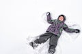 Cute little kid boy in colorful winter clothes making snow angel Royalty Free Stock Photo