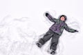 Cute little kid boy in colorful winter clothes making snow angel Royalty Free Stock Photo