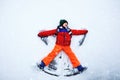 Cute little kid boy in colorful winter clothes making snow angel, laying down on snow. Active outdoors leisure with Royalty Free Stock Photo