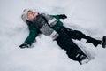 Cute little kid boy in colorful winter clothes making snow angel, laying down on snow. Active outdoors leisure with Royalty Free Stock Photo