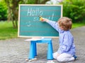 Cute little kid boy with glasses at blackboard practicing writin Royalty Free Stock Photo