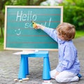 Cute little kid boy with glasses at blackboard practicing writing Royalty Free Stock Photo