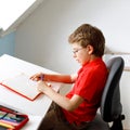 Cute little kid boy with glasses at home making homework, writing letters with colorful pens. Little child doing Royalty Free Stock Photo