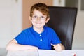 Cute little kid boy with glasses at home making homework, writing letters with colorful pens. Little child doing Royalty Free Stock Photo