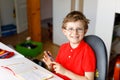 Cute little kid boy with glasses at home making homework, writing letters with colorful pens. Royalty Free Stock Photo