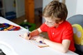 Cute little kid boy with glasses at home making homework, writing letters with colorful pens. Royalty Free Stock Photo