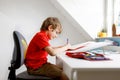 Cute little kid boy with glasses at home making homework, writing letters with colorful pens. Royalty Free Stock Photo