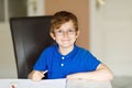 Cute little kid boy with glasses at home making homework, writing letters with colorful pens. Royalty Free Stock Photo
