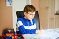 Cute little kid boy with glasses at home making homework, writing letters with colorful pens. Little child doing Royalty Free Stock Photo
