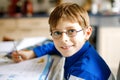 Cute little kid boy with glasses at home making homework, writing letters with colorful pens. Little child doing Royalty Free Stock Photo