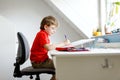 Cute little kid boy with glasses at home making homework, writing letters with colorful pens. Royalty Free Stock Photo