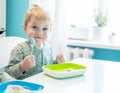 Cute little kid boy hungry eating healthy food in kitchen at home, holding spoon Royalty Free Stock Photo