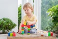 Cute little kid boy with playing with lots of colorful plastic blocks indoor. Active child having fun with building and creating o Royalty Free Stock Photo