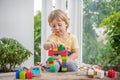 Cute little kid boy with playing with lots of colorful plastic blocks indoor. Active child having fun with building and Royalty Free Stock Photo