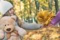 Cute little kid daughter congratulating mum with mothers day, smiling girl with Teddy bear presents autumn yellow leaves Royalty Free Stock Photo