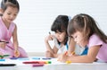 Cute little kid girl concentrate with using two hands drawing on paper while sitting and lying on floor with friends. Adorable Royalty Free Stock Photo