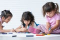 Cute little kid girl concentrate with using two hands drawing on paper while sitting and lying on floor with friends. Adorable Royalty Free Stock Photo