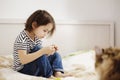 Cute little kid girl sitting on a bed alone with cat playing with serious face Royalty Free Stock Photo