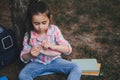 Cute little kid girl, smart primary school student opening her pencil case while doing homework in the park after class Royalty Free Stock Photo