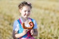 Cute little kid girl in traditional Bavarian costume in wheat field. German child with hay bale during Oktoberfest in