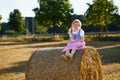 Cute little kid girl in traditional Bavarian costume in wheat field. Happy child with hay bale during Oktoberfest in Royalty Free Stock Photo