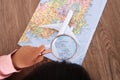 Cute little kid looking at map of Japan with magnifying glass in hand