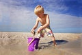 Cute Little Kid Playing with Sand in a Bucket at the Beach by the Ocean