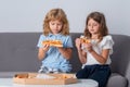 Cute little kids boy and girl eating Pizza at home. Children holding a slices of pizza on party at home. Two young Royalty Free Stock Photo