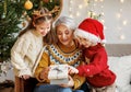 Little children granddaughter and grandson giving Christmas gift box to smiling grandmother during winter holidays Royalty Free Stock Photo