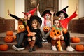 Cute little kids with pumpkins wearing Halloween costumes on stairs outdoors Royalty Free Stock Photo