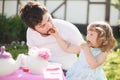 Cute little lady playing tea party with her caring father